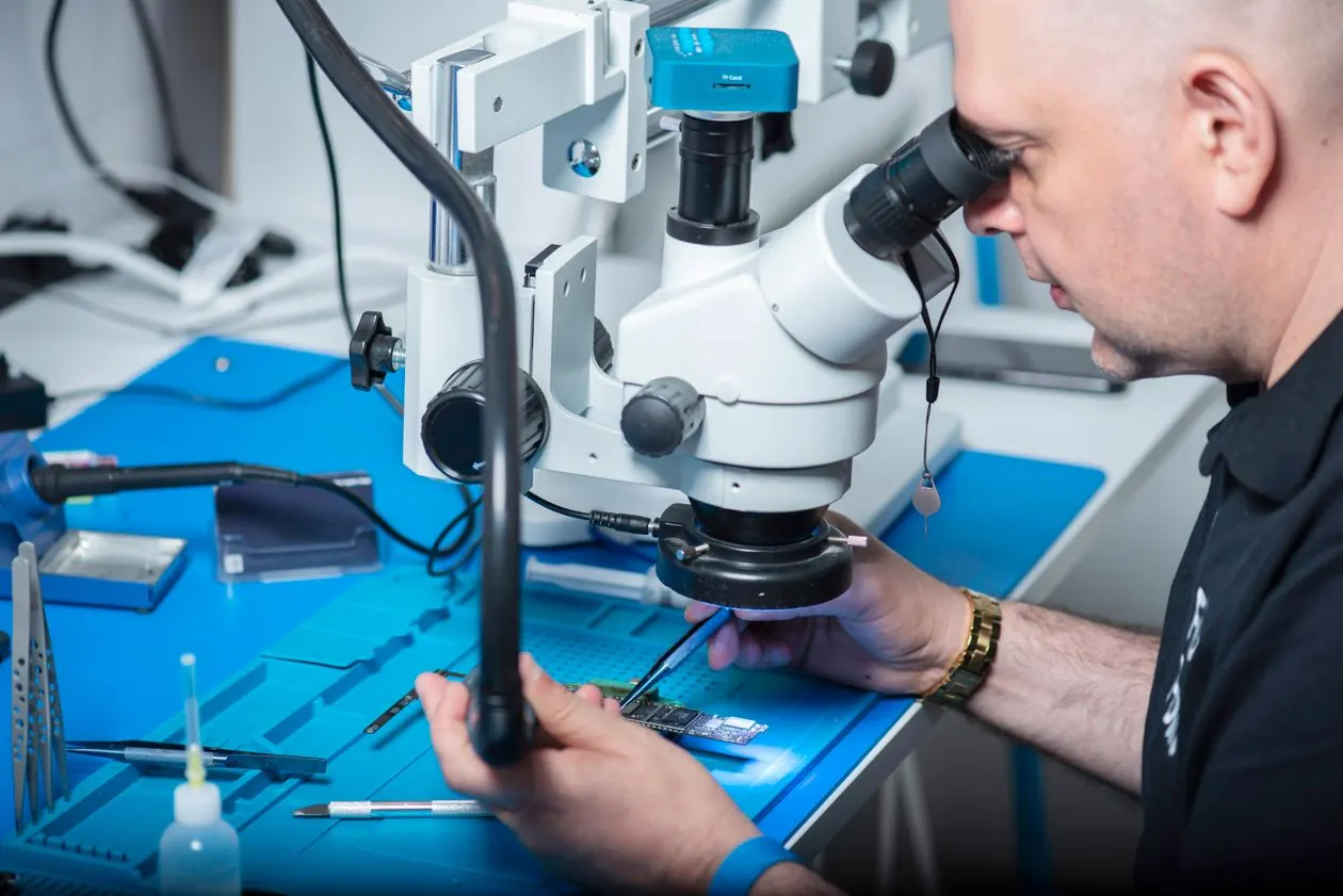 Technician using a microscope for precision smartphone repair